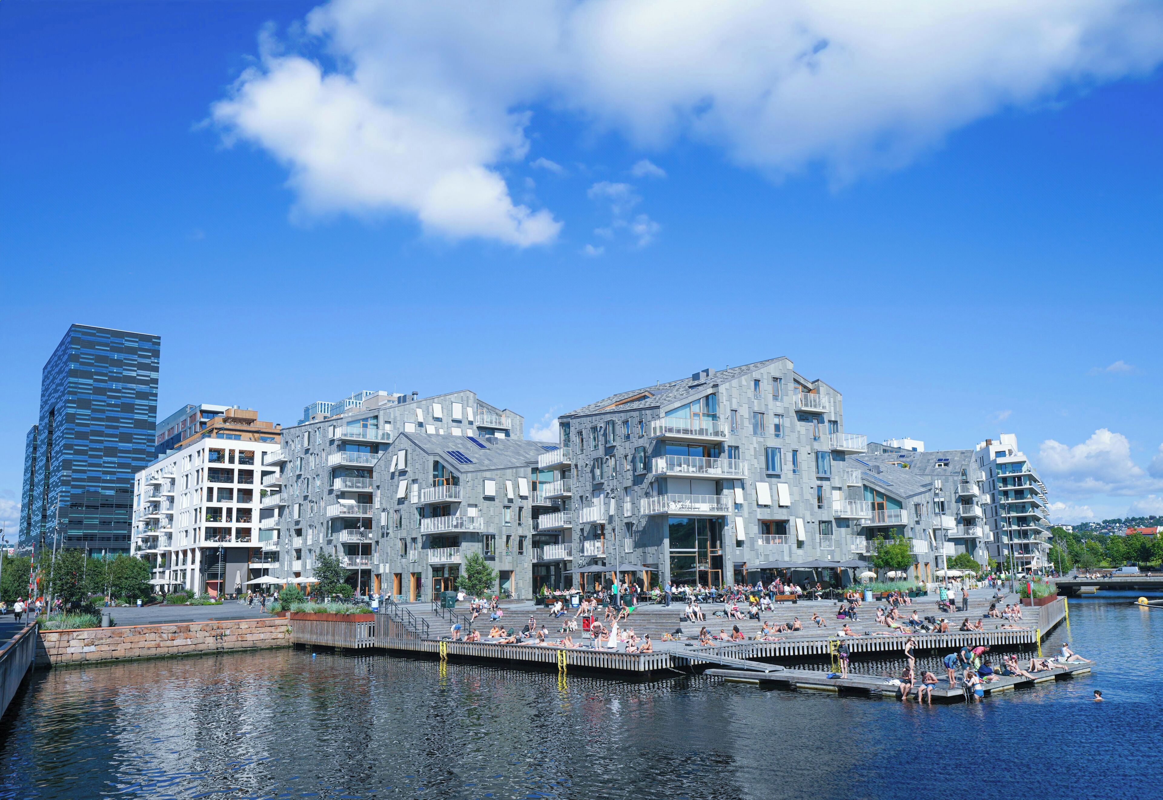 A waterfront building with multiple balconies, a dock, and a clear sky.