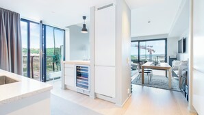 A modern living room with a dining area, large windows, and a kitchen with a wine cooler. - Central Penthouse on 19th Floor with Amazing View (Oslo)