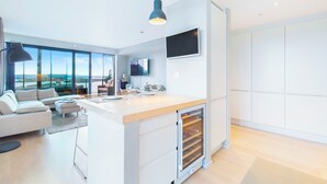 A modern kitchen with a central island, a built-in wine cooler, and a large window offering a city view. - Central Penthouse on 19th Floor with Amazing View (Oslo)