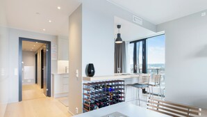 A modern kitchen with a wine rack, a dining area with a bench, and a view through large windows. - Central Penthouse on 19th Floor with Amazing View (Oslo)