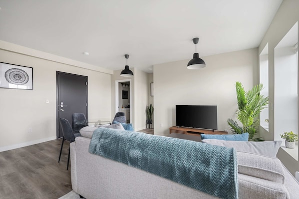 A modern living room with a sofa, TV, and plants.