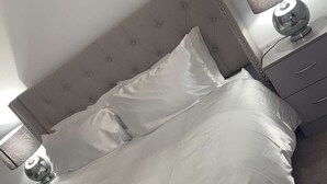 A neatly made bed with white linens and a tufted headboard. - Apartment With Space in Parking (Barking)