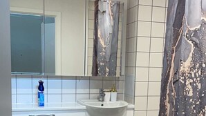 A modern bathroom with a toilet, sink, and shower curtain. - Apartment With Space in Parking (Barking)