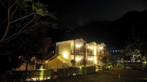 A two-story building with a symmetrical facade, illuminated by exterior lighting. - Aspen Adventures Camp by Aspen (Rishikesh)