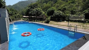 A swimming pool with two red lifebuoys and a ladder. - Aspen Adventures Camp by Aspen (Rishikesh)