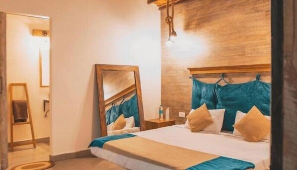 A bedroom with a bed, a wooden headboard, a mirror, and a nightstand.