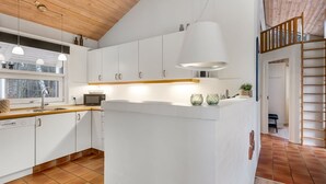 Une cuisine moderne avec des armoires blanches, un plafond en bois et un îlot central.