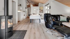 Un intérieur moderne avec un poêle à bois, un coin repas et un canapé en cuir.