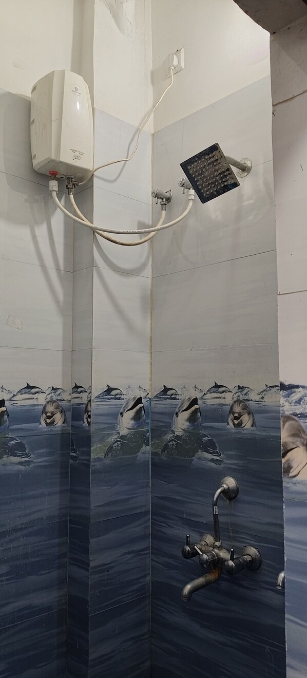Un espace douche équipé d’un chauffe-eau, d’un pommeau de douche à main et d’un mur carrelé orné d’une fresque représentant la vie marine.