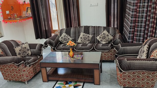 A living room with a sofa set, coffee table, and patterned armchairs. - Hariom Home Stay By GRB (Faizabad)