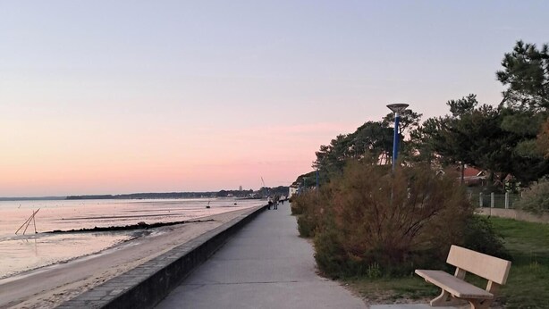 Un paseo marítimo con un banco, un farol y una vista despejada del mar.