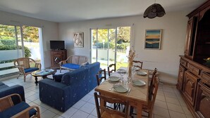 Un salón amplio con sofá, mesa de comedor preparada para cuatro personas y televisor.