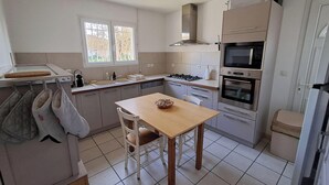 Una cocina compacta con una mesa de madera, un lavamanos, una estufa y un microondas.