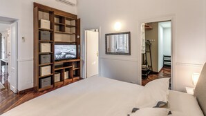 A bedroom with a large bed, a wooden storage unit, a television, and a mirror on the wall. - Spacious Apt in the Center of Rome  (Roma)