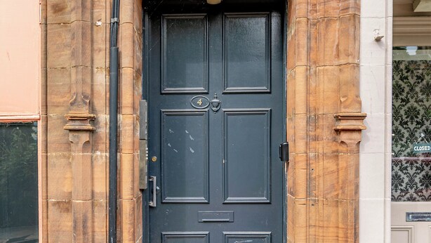 A black door with a number "4" above it, set within a stone facade with decorative elements. - Spacious City Apartment - Dunfermline (Dunfermline)