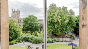A view of a courtyard with a stone building, lush greenery, and a pathway. - Spacious City Apartment - Dunfermline (Dunfermline)