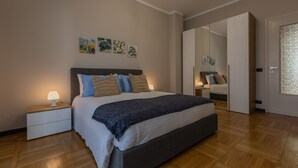A modern bedroom with a large bed, bedside lamps, and artwork on the wall. - Torino Modern Stay by Wonderful Italy (Turin)