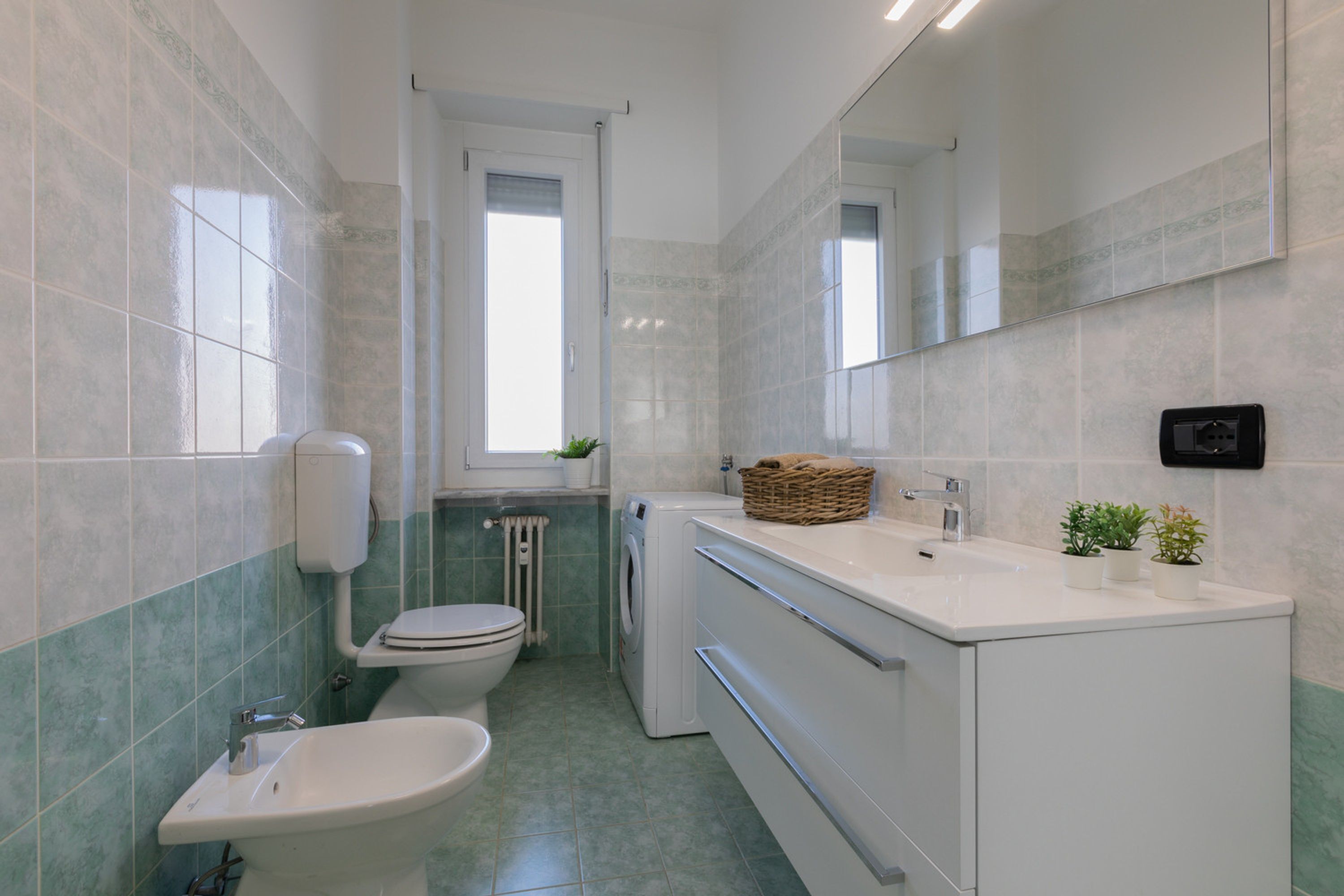 A compact bathroom with a toilet, bidet, and washing machine.