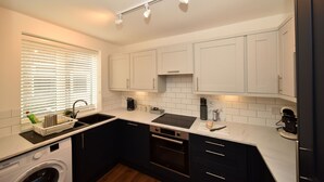 Una cucina moderna con mobili bianchi, forno a incasso, lavello e lavastoviglie.