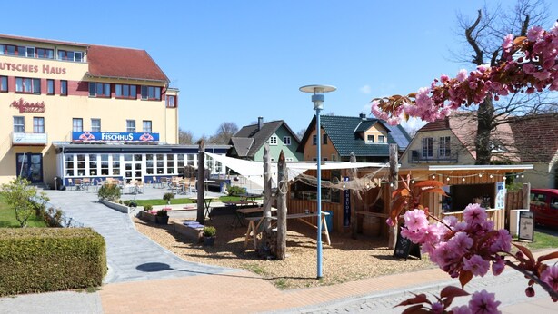 A building with a sign reading "FISCHHUS" and a restaurant with outdoor seating.