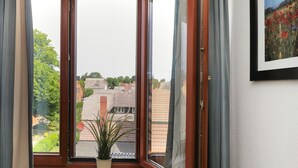 A room with a large window, a potted plant, and a framed picture on the wall.