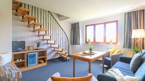 Una sala de estar moderna con una escalera espiral, un sofá, una mesa y un televisor.