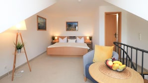 Un dormitorio con una cama, mesitas de noche con lámparas, una mesita con fruta, una planta y un cuadro en la pared.