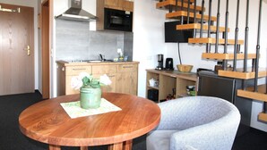 Une cuisine de taille réduite, dotée de meubles en bois, d’un four à micro-ondes et d’une machine à café.