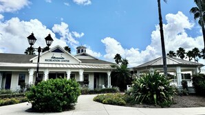 Das Allamanda Recreation Center mit überdachter Eingang, blauem Himmel und umliegender Bepflanzung.