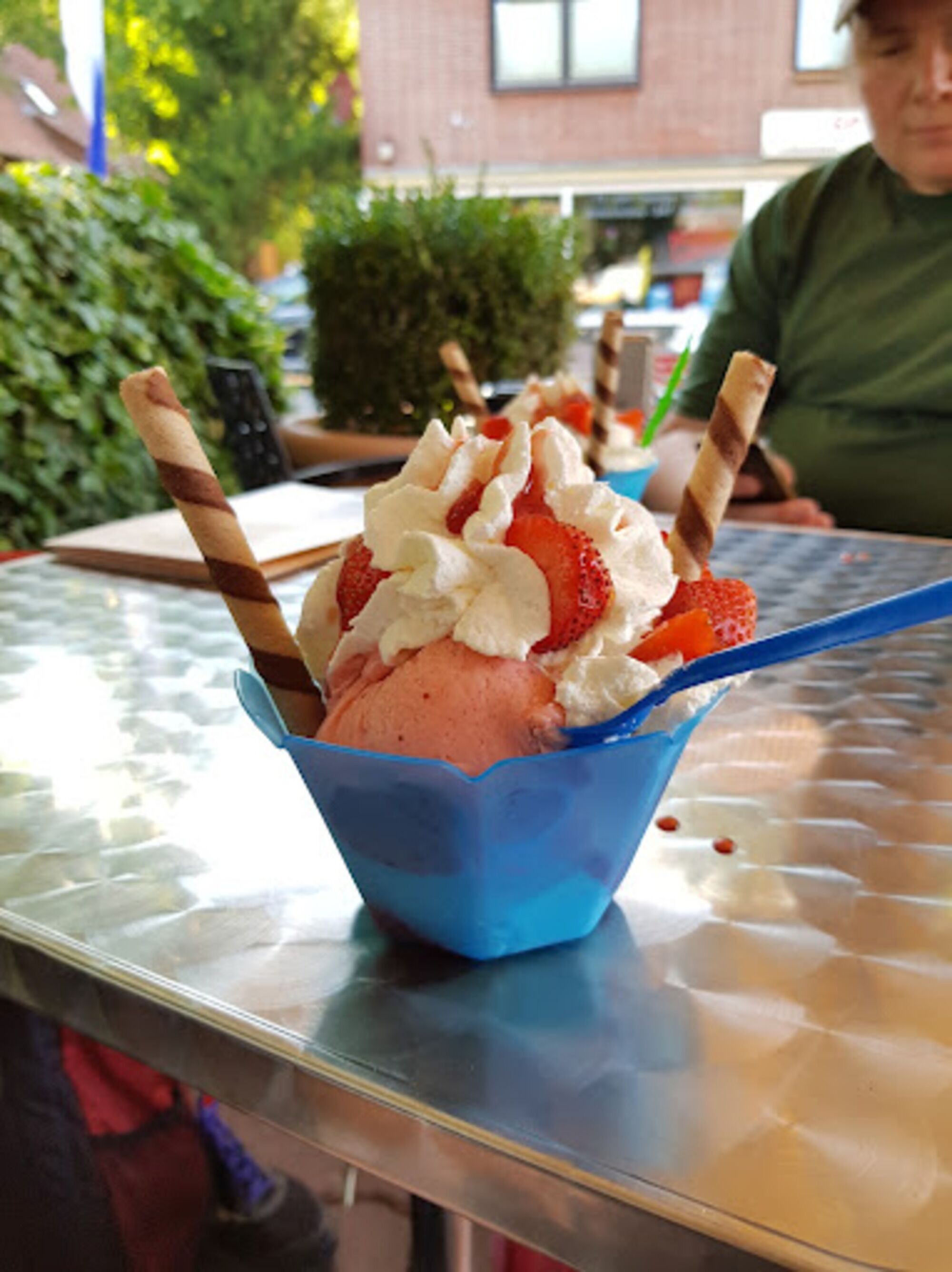 Ein Dessert in einer blauen Tasse mit Löffel, auf einem Tisch platziert.