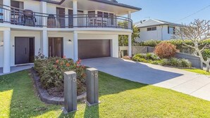 A two-story house with a balcony, a garage, and a well-maintained lawn.