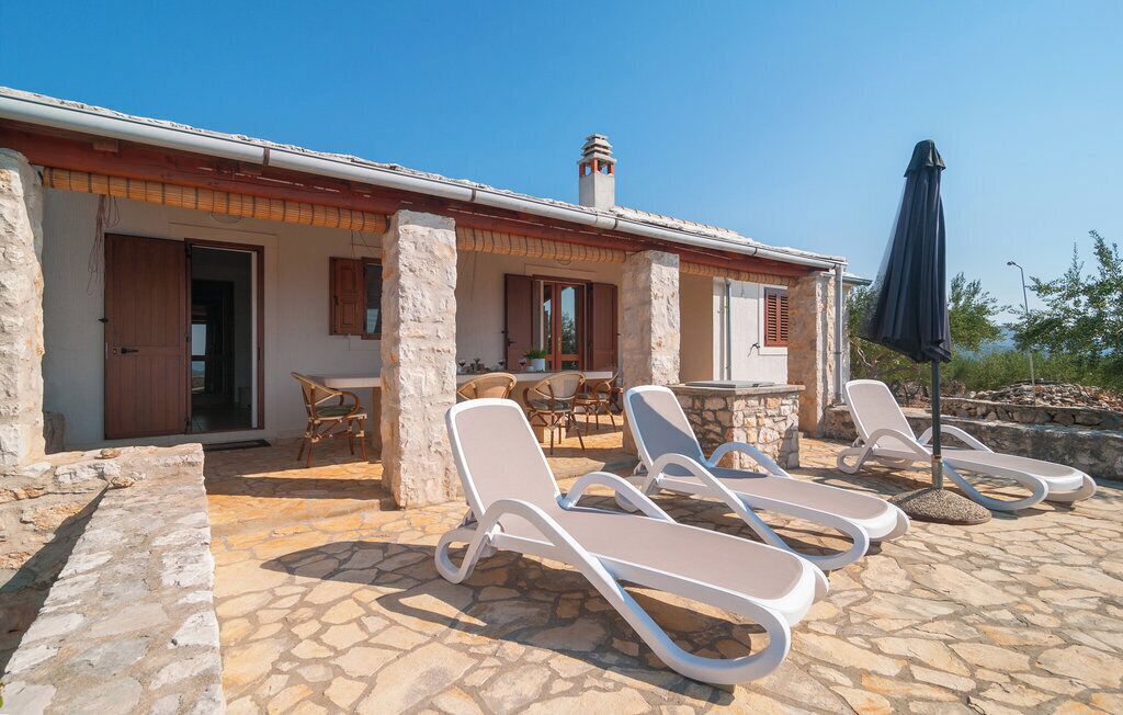 A stone building with a tiled patio, outdoor seating, and lounge chairs.