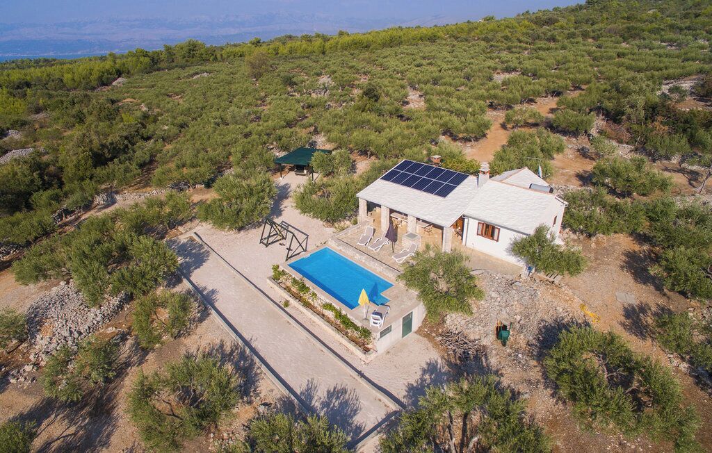 Una casa con piscina, paneles solares y vistas del paisaje circundante.