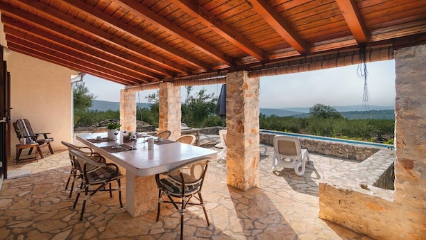 An outdoor patio with a stone table and chairs, a wooden ceiling, and a view of the landscape. - Holiday Home Stomorica (Sutivan)