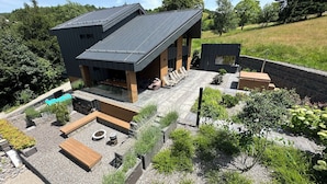 Une maison moderne avec un toit en pente, un espace extérieur aménagé et une piscine.