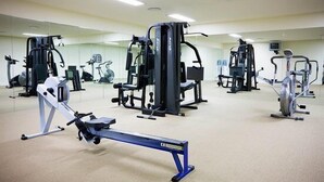 Un gimnasio con diversas máquinas de ejercicio, incluyendo una máquina de remo, una prensa de piernas y una bicicleta estática.
