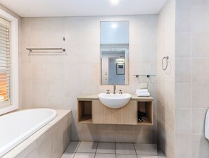 Een moderne badkamer met een bad, een wastafel met spiegel erboven en een handdoekrek.