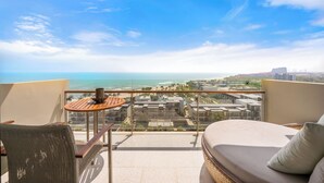 Un balcón con vista al océano, una mesa, una silla y un sofá.