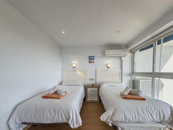 Una habitación de hotel con dos camas, un escritorio pequeño y una ventana.