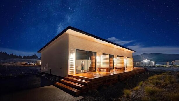 A modern house with a wooden deck and large windows, set against a starry night sky. - Alpine Studio Coulson (Lake Tekapo)