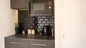 A modern kitchen with a microwave, coffee maker, and knife block. - Alpine Studio Coulson (Lake Tekapo)