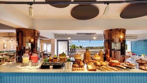 Un bufé con diferentes opciones de comida y una barra con vasos y aderezos.