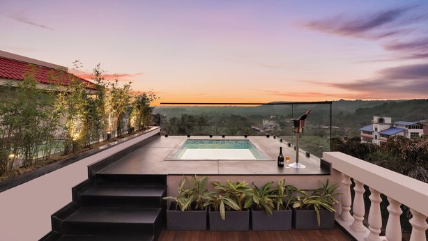 Una terraza en la azotea con piscina, escalones de acceso y vistas al paisaje.