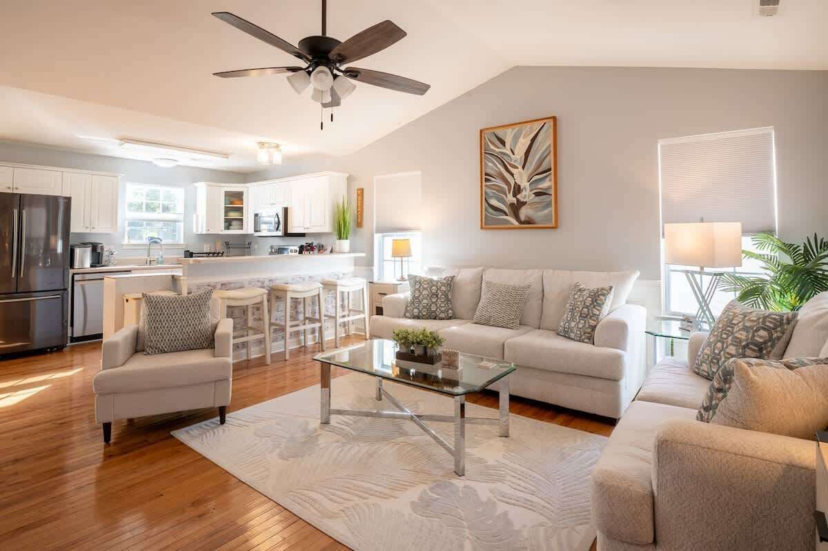 A modern living room with a glass coffee table, a sofa, and a ceiling fan.