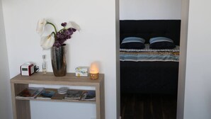 A bedside table with a vase of flowers, a lamp, and a few books. - 2 pieces, garden level, Vue imprenable sur le Lac Léman (Évian-les-Bains)