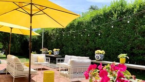 An outdoor patio with yellow furniture, a large umbrella, and potted plants. - Maxson House Mystic – Easy Walk to Downtown (Mystic)