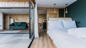 A modern bedroom with a large bed, a green sofa, and a wooden wall. - Dyffryn Ceri - luxury converted shipping container (Penuwch)