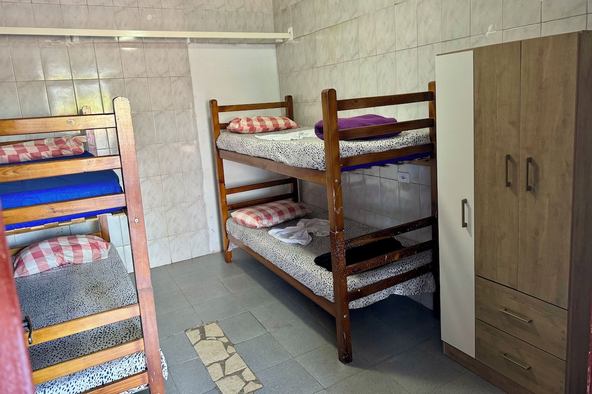 Une chambre de dortoir avec des lits superposés, une armoire et des murs carrelés.