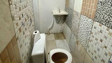 Un baño pequeño con inodoro, lavamanos y espejo. Las paredes están cubiertas de azulejos con distintos diseños.