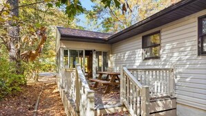 A cabin with a covered porch, a picnic table, and a staircase leading to the entrance. - Ocean Pines Hideaway (Ocean Pines)